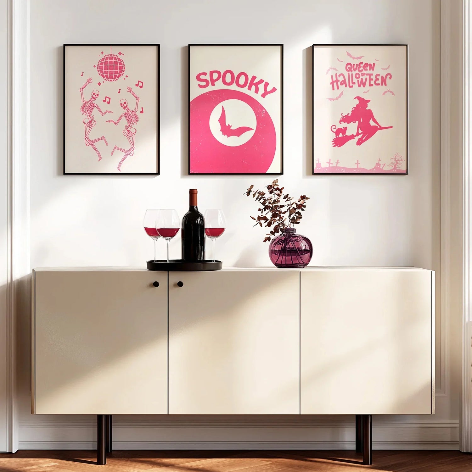 Modern interior with a sideboard, wine glasses, and decorative items against a wall with Halloween-themed pink posters.